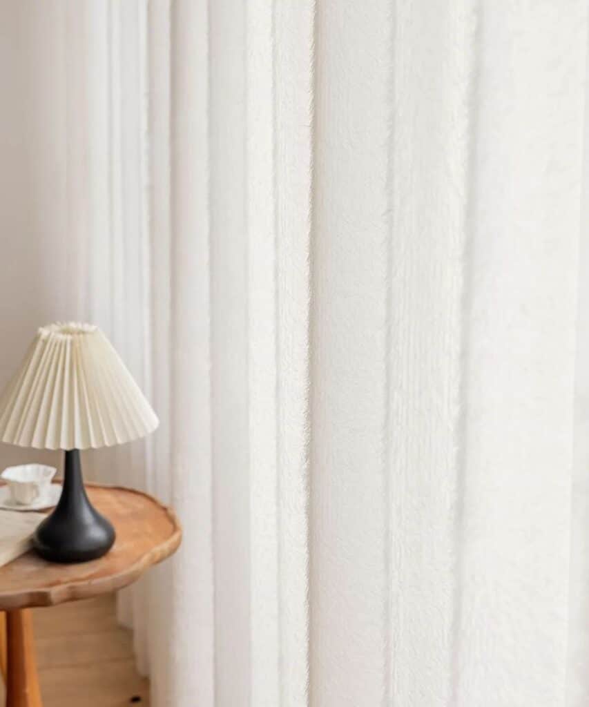 closeup of sheer curtain with side table and lamp next to it