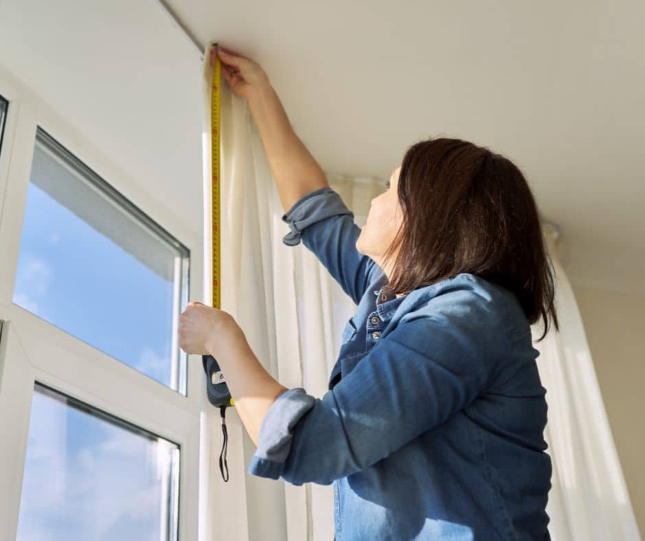 woman measuring and installing sheer curtains